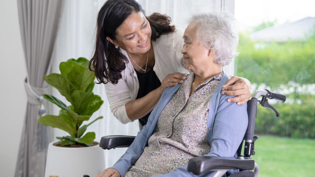 caregiver assisting elderly parent with brushing teeth at bathroom sink