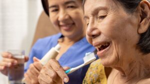caregiver helping elderly parent with daily caregiver helping elderly parent with daily dental care routine