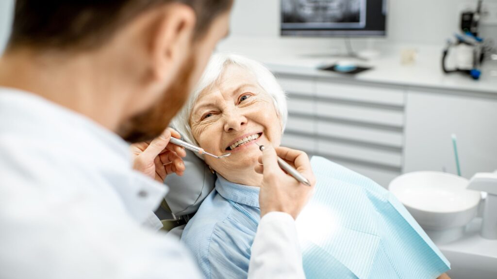 dentist examining elderly patient's gums for signs of periodontal disease