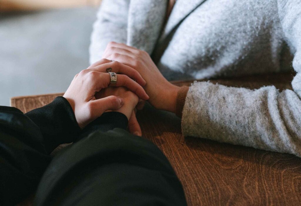 Family member holding the hand of a parent in the final stage of dementia